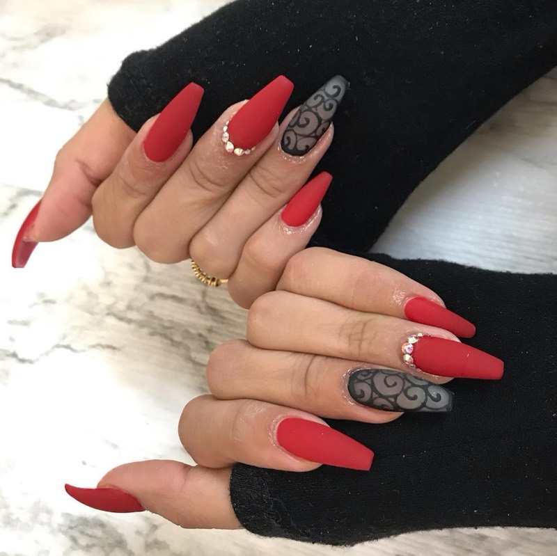 Matte red coffin nails with crystal accents and two grey filigree feature nails